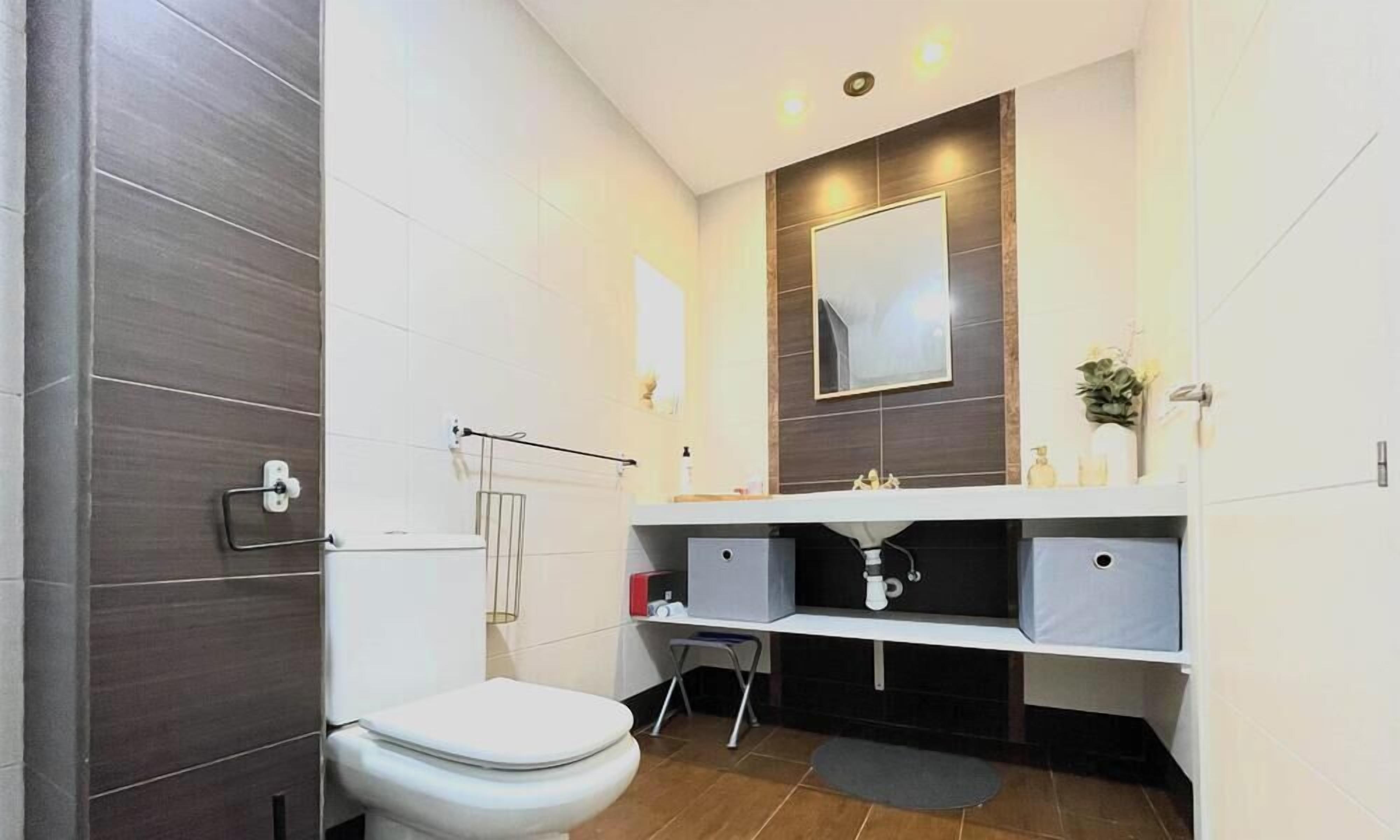 Ein modernes Badezimmer mit Toilette, Waschbecken und Spiegel.