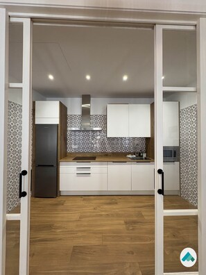 A modern kitchen with wooden cabinets, a stainless steel refrigerator, and patterned backsplash. - Peace of Mind: Córdoba (Córdoba)