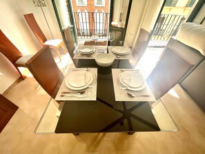 Un coin repas avec une table en verre, dressée pour quatre personnes, entourée de chaises.