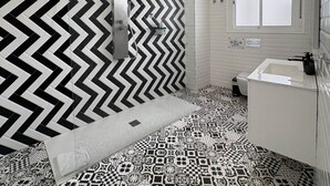 A bathroom with a black and white chevron-patterned wall, a patterned floor, a white sink, and a window. - Rest in the Heart: Córdoba (Córdoba)