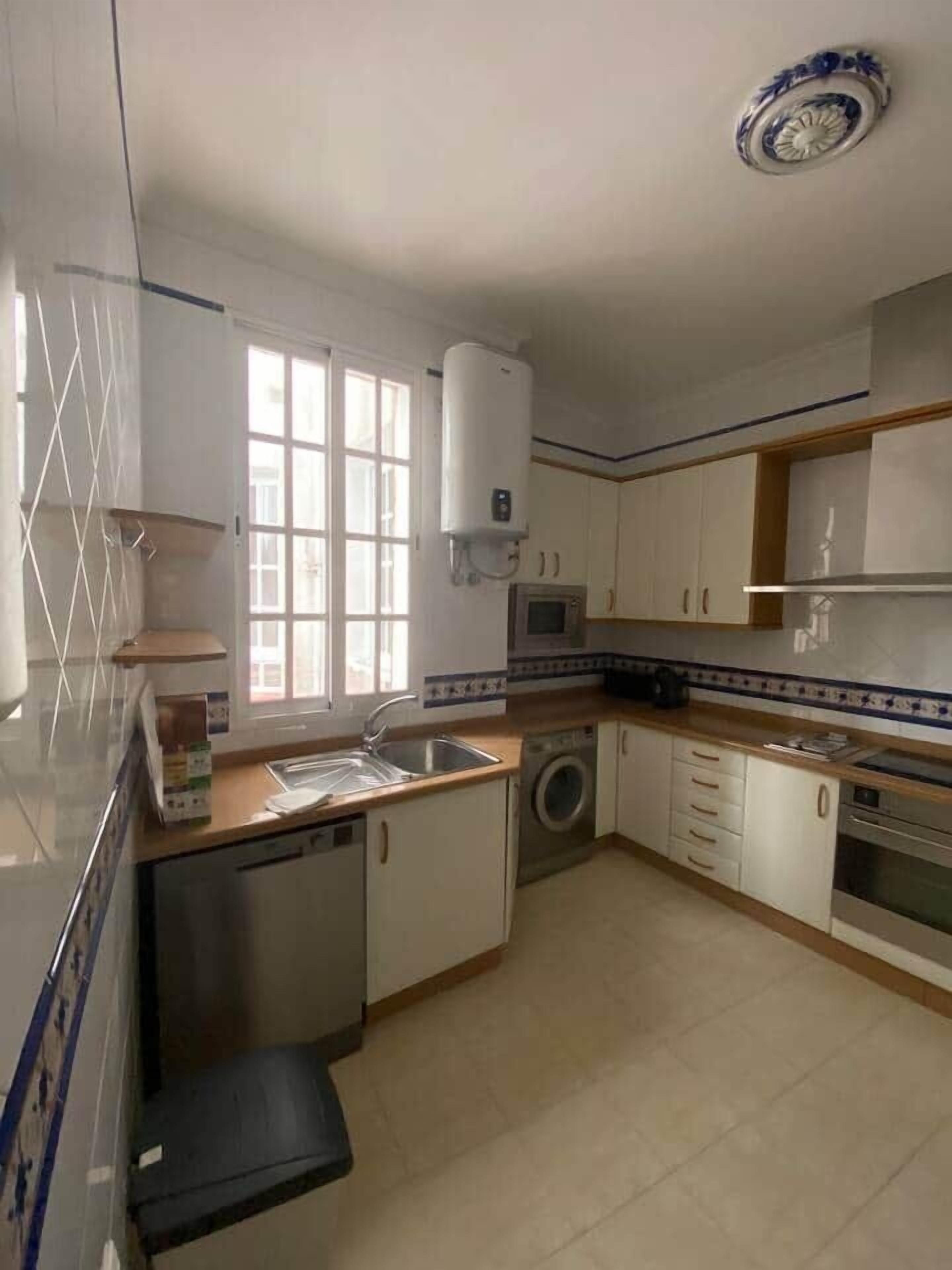 A kitchen with a dishwasher, washing machine, microwave, and a water heater.