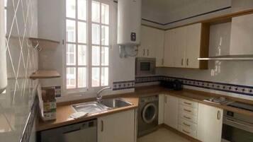 A kitchen with a dishwasher, washing machine, microwave, and a water heater.