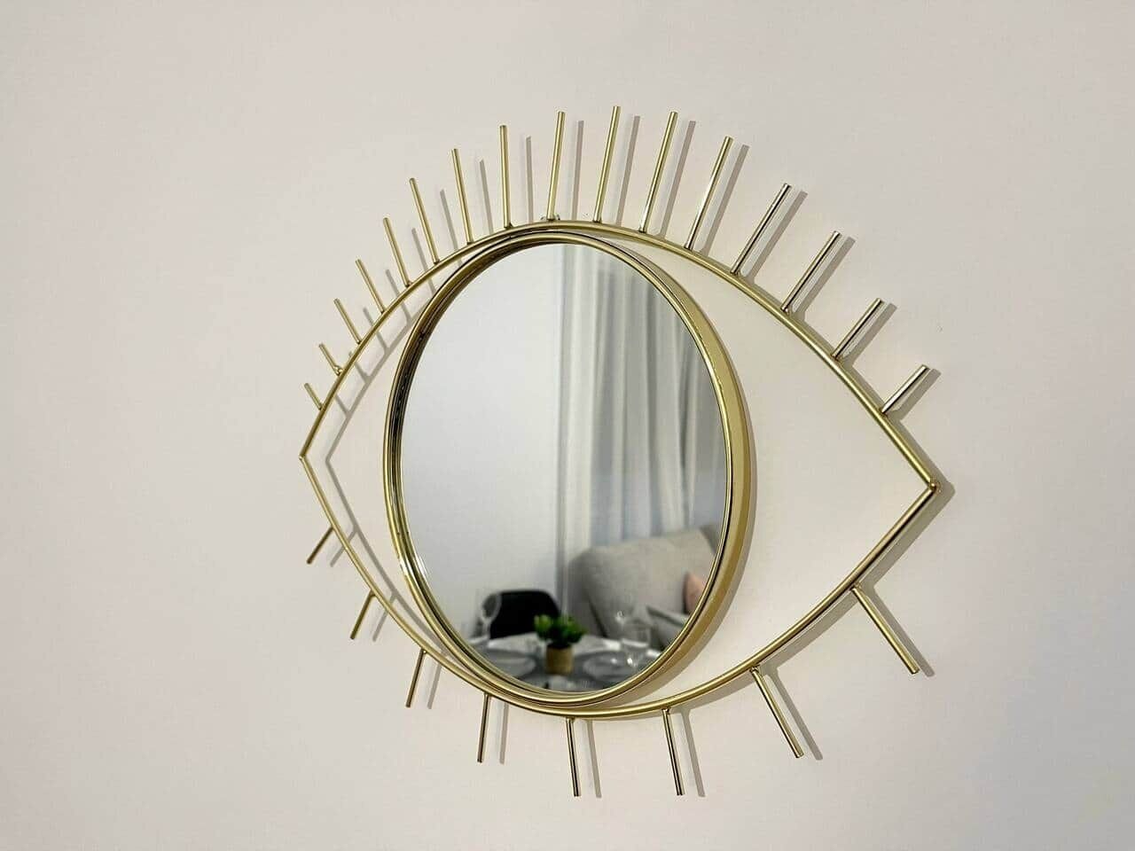 Un miroir mural doté d’un cadre original en forme d’œil.