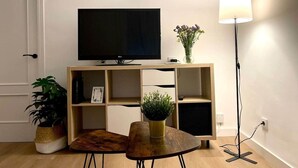 Un salon équipé d’un téléviseur à écran plat, d’étagères en bois, d’une table basse et d’un lampadaire.