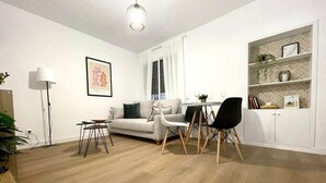 Un salon moderne comprenant un canapé, une table à manger et des chaises, un lampadaire et une bibliothèque.