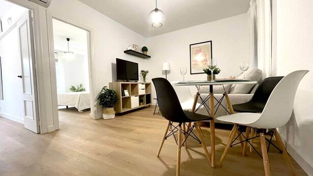Un espace repas moderne avec un plancher en bois, une table en verre et des chaises noires et blanches.