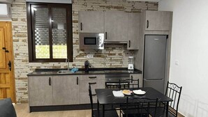 Una cocina compacta con armarios grises, microondas integrado y refrigerador.