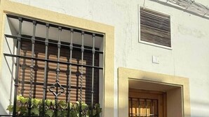 Un edificio con una ventana con barrotes y una puerta de madera.
