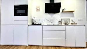 Una cucina moderna con mobili bianchi, un forno a microonde nero e un piccolo ripiano con oggetti decorativi.