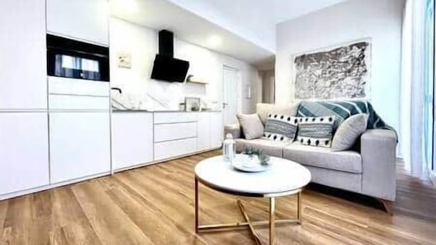Un soggiorno moderno con un divano, un tavolino da caffè e una zona cucina con mobili.