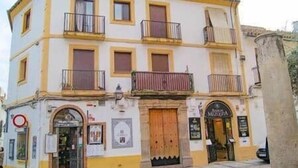 A two-story building with a yellow and white facade, multiple balconies, and a large wooden door. - New Mosque2-Mezquita Cathedral (Córdoba)