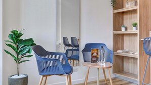 A modern room with two blue chairs, a small round table, a potted plant, and a wooden shelf with decorative items. - w* |  Stylish & Cozy Duplex Loft in Zona G (Bogotá)