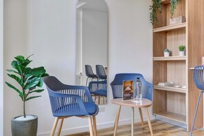 Ein modernes Zimmer mit zwei blauen Stühlen, einem kleinen runden Tisch, einer Topfpflanze und einem Holzboden mit Dekoration.