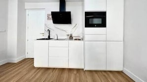 Uma cozinha compacta com armários brancos, um micro-ondas preto e uma pia.