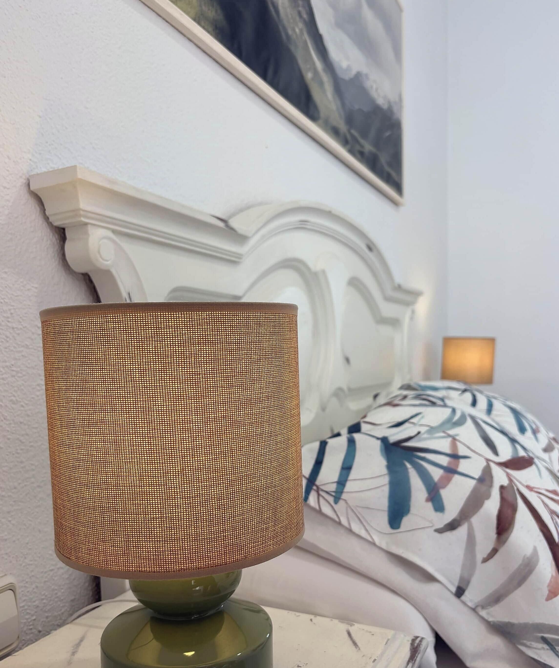 A lamp with a woven shade on a bedside table.