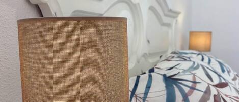 A lamp with a woven shade on a bedside table.