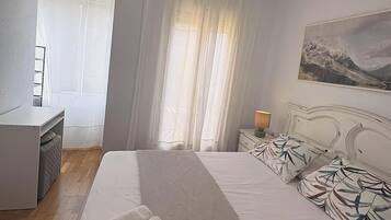 Een hotelkamer met een bed, een bureau, een stoel, een nachtkastje met een lamp en een schilderij aan de muur.