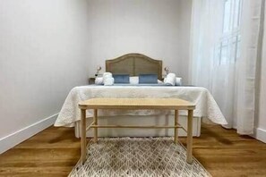 Une chambre à coucher avec un lit, une table de chevet en bois et un tapis tissé.