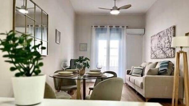 A dining area with a table set for two, a sofa, and a ceiling fan. - House in City Garden 3 (Córdoba)