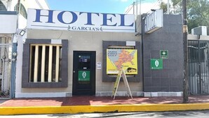 Un hotel llamado "HOTEL GARCIA'S" con un letrero, un mapa y una señal verde que indica un punto de interés.