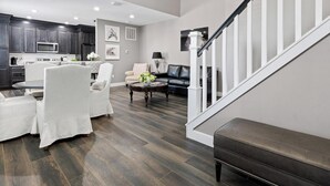 Una sala de estar moderna con comedor, escalera y cocina.
