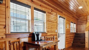 Interior de madera con una mesa de comedor, sillas y una escalera.
