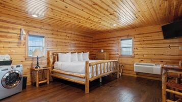 L'intérieur d'une cabane en bois, avec un lit, une machine à laver et un téléviseur.