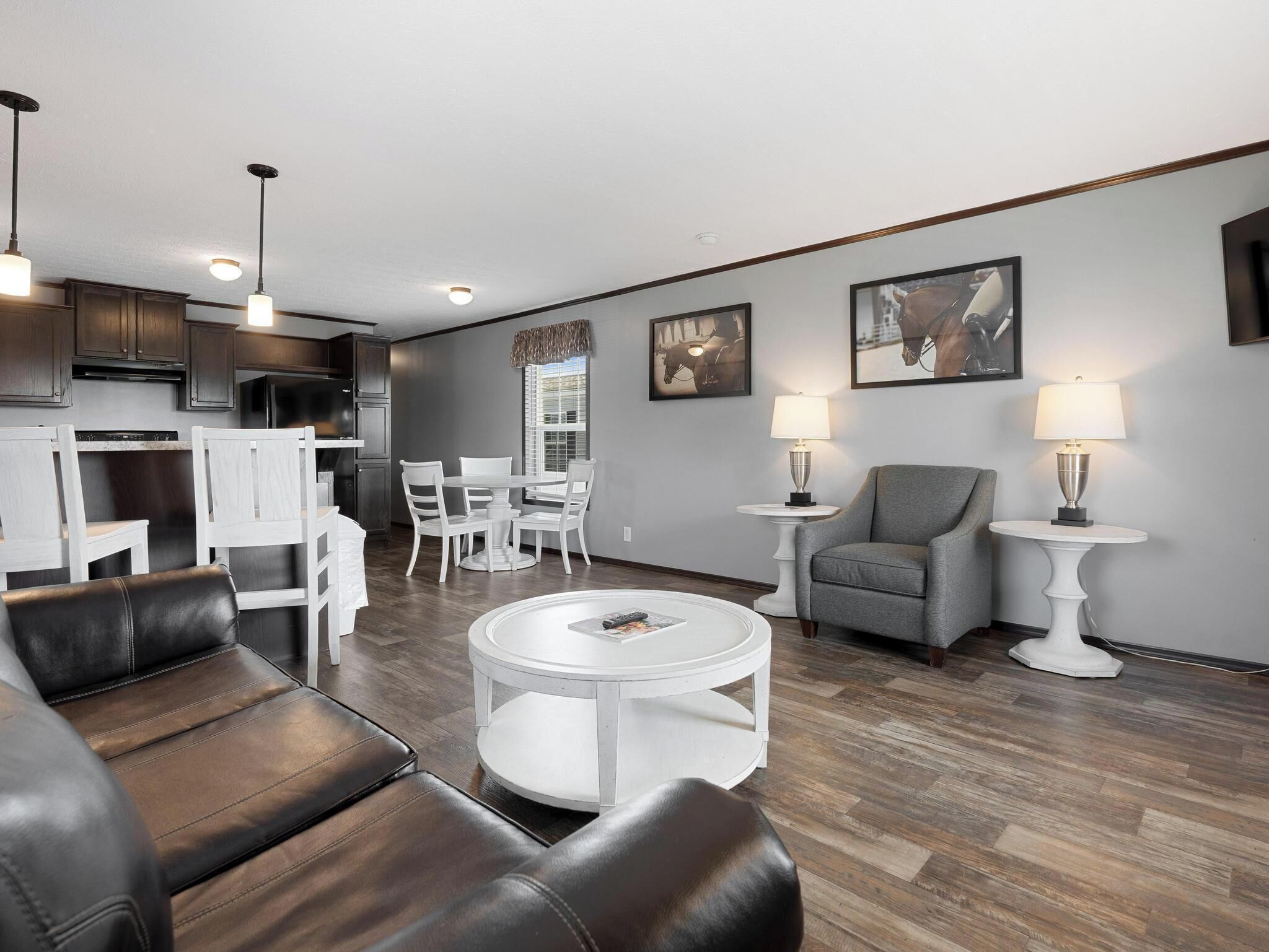 A modern living room with a dining area, leather sofas, a white coffee table, and two standing lamps.