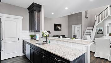 A modern kitchen with dark cabinetry, a marble countertop, and a built-in island.