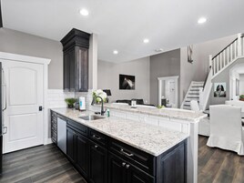Cocina moderna con muebles oscuros, encimera de mármol y una isla integrada.