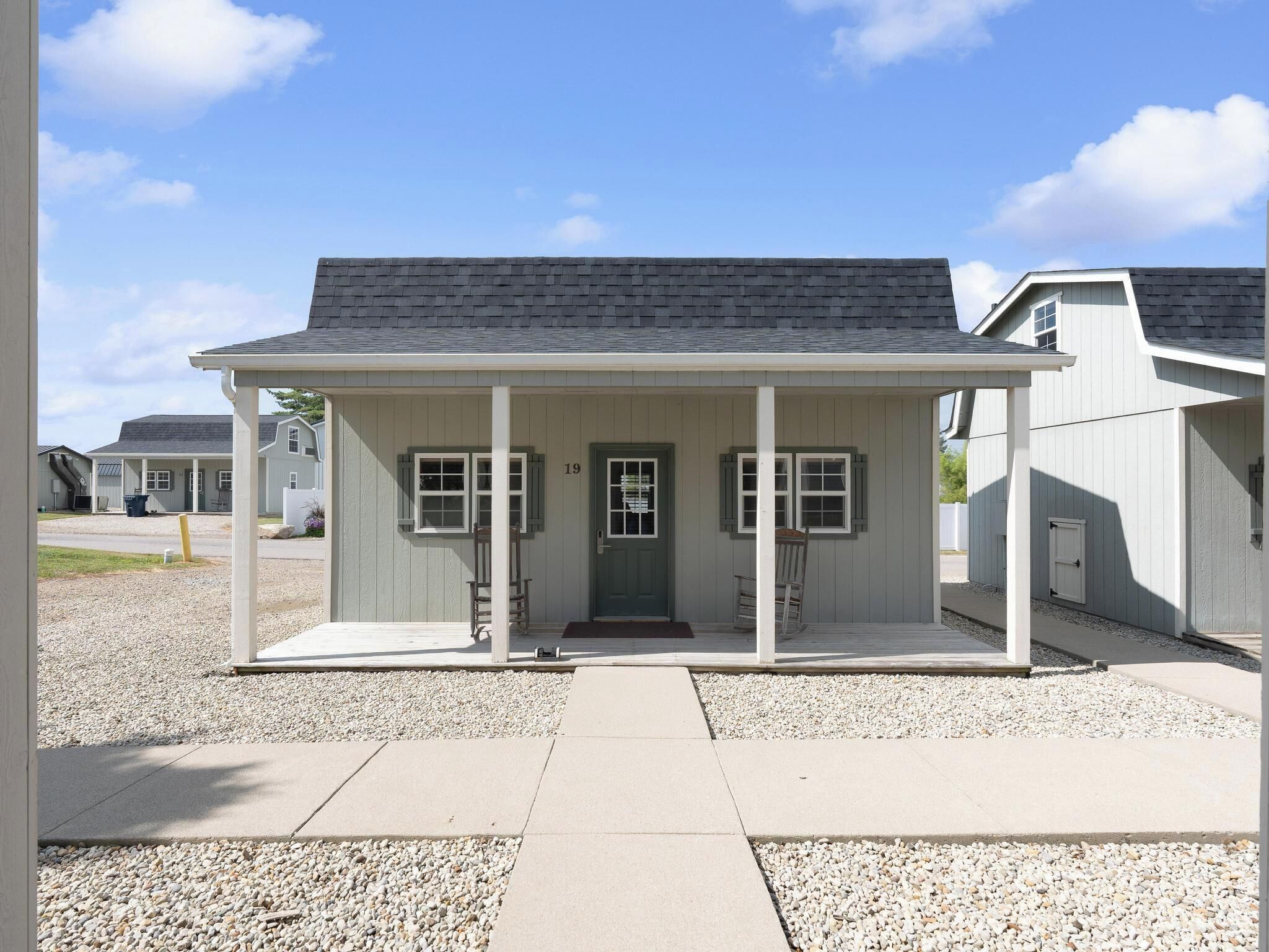A single-story building with a front porch, a door, and a number '19' on the door.