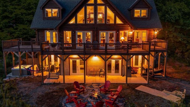 A large log cabin with multiple decks, outdoor seating, and a fire pit. - Luxury Log Cabin with Hot Tub, Game Room & Theater and Mountain Views (Black Mountain)