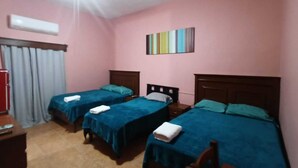 A room with three single beds, a ceiling fan, a window with curtains, and a small table with a red object. - García's Suites y Hotel Villegas (Linares)