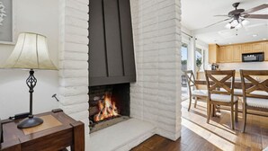 Een kamer met een open haard, houten meubels en een plafondventilator.