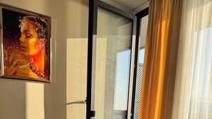 Un salon moderne avec un ordinateur portable posé sur une table, une porte vitrée, un fauteuil bleu et une petite plante en pot.