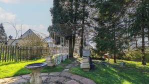 A garden pathway with a decorative metal fence, a stone fountain, and a stone bench.