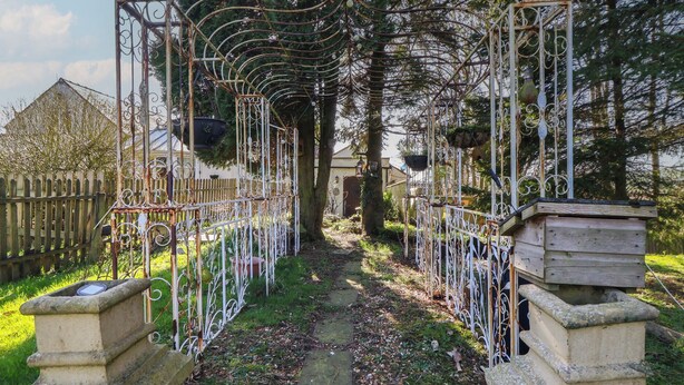 A garden pathway with ornate metal fencing and stone structures.