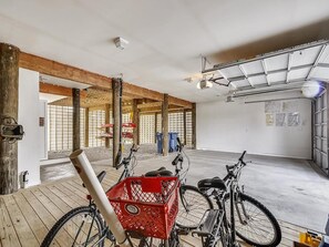 A spacious indoor area with wooden beams, bicycles, and a red basket. - Modern 4BR House near Bethany Beach | Decks & Pool (Bethany Beach)