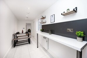 A modern kitchen with white cabinetry, a black backsplash, and a dining area with a bench. - Sleeps 5, 2 Bed Flat In The Lanes, Brighton (Brighton and Hove)