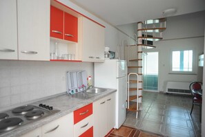 A kitchen with white and red cabinets, a stainless steel stove, and a built-in microwave. - Golden Coast Villa Caska (Novalja)