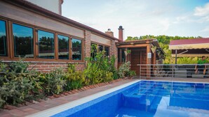 A swimming pool with a tiled edge, surrounded by a brick wall and various plants. - Golden Coast Villa Caska (Novalja)