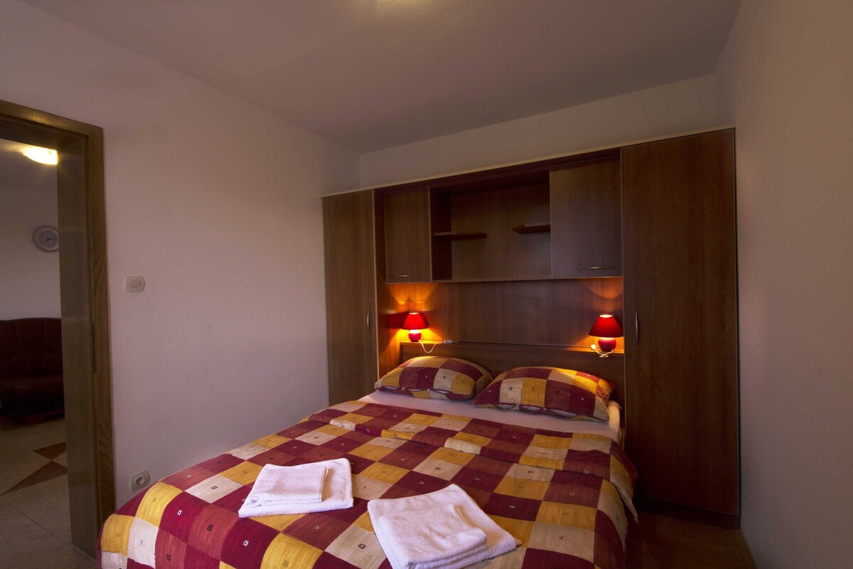 A hotel room with a large bed, two bedside lamps, and a wooden wardrobe.