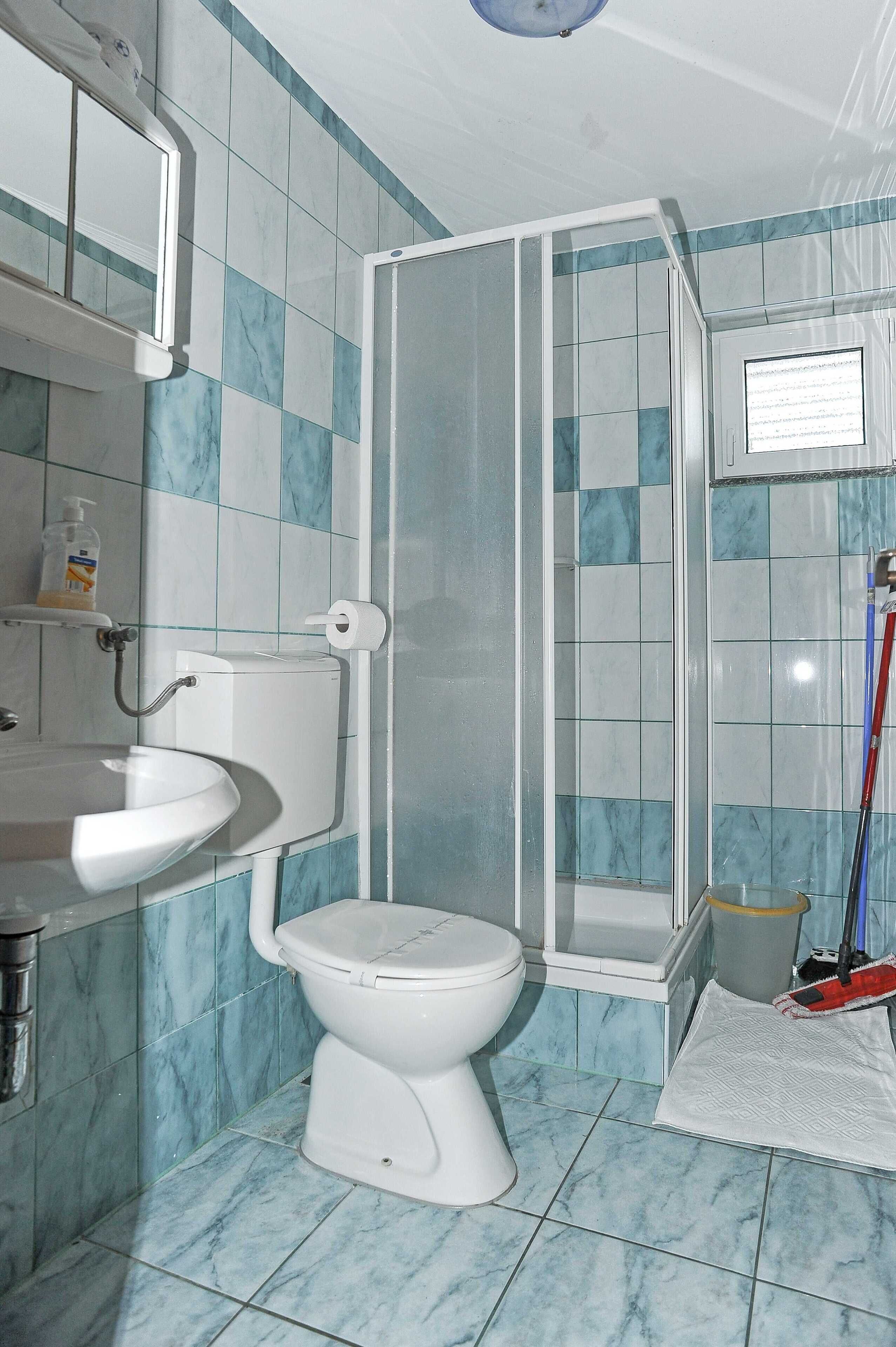 A bathroom with a toilet, sink, and shower enclosure.