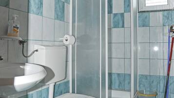 A bathroom with a toilet, sink, and shower enclosure.