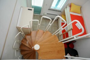 A spiral staircase with white railings and a wooden finish, leading to a bed with red bedding and yellow pillows. - Golden Coast Villa Caska (Novalja)