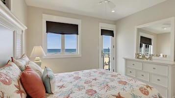 Un dormitorio con cama, ventilador de techo, cómoda, ventana con vistas y puerta que da a un balcón.