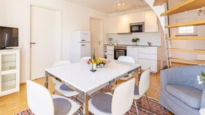 A modern, compact living space with a dining area, kitchenette, and a seating area with a sofa. - Ferienresidenz Hinterzarten FEWO H9 (Hinterzarten)