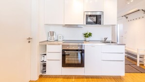 A modern kitchen with white cabinetry, a stainless steel oven, a microwave, and a coffee maker. - Ferienresidenz Hinterzarten FEWO H9 (Hinterzarten)