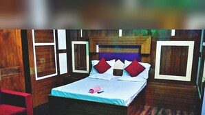 Un dormitorio con cama, almohadas, una mesita y una silla.