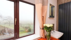 A bathroom with a window, a sink, and a vase with flowers. - Dilston House (Whitby)